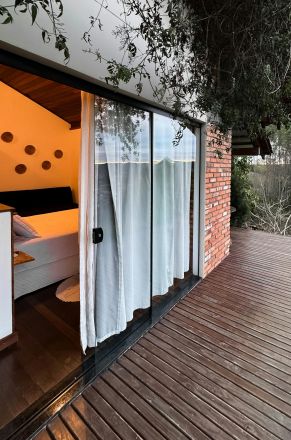 Brick house with wooden deck and outdoor greenery, showcasing modern architecture.