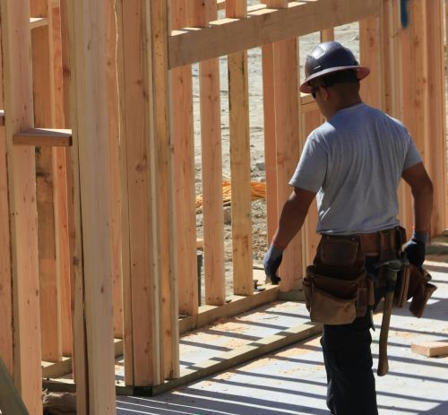 Construction worker on site building wooden frame home during the day.