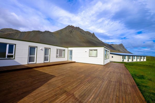 Exterior view of a modern bungalow with a scenic mountain backdrop and clear blue skies.