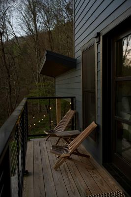 Peaceful outdoor deck with wooden chairs overlooking a serene forest at dusk.