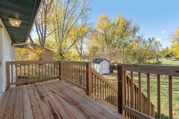 A spacious wooden deck with a view of a vibrant autumn backyard, perfect for relaxation.