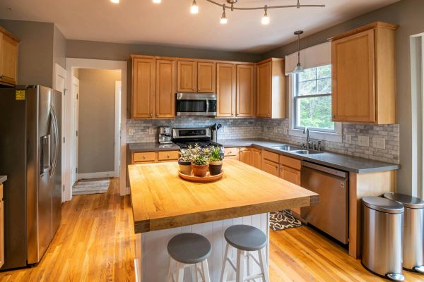 A modern kitchen featuring wooden cabinets, island, and stainless steel appliances.