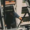A man climbing a fire escape on a city building on a sunny day.
