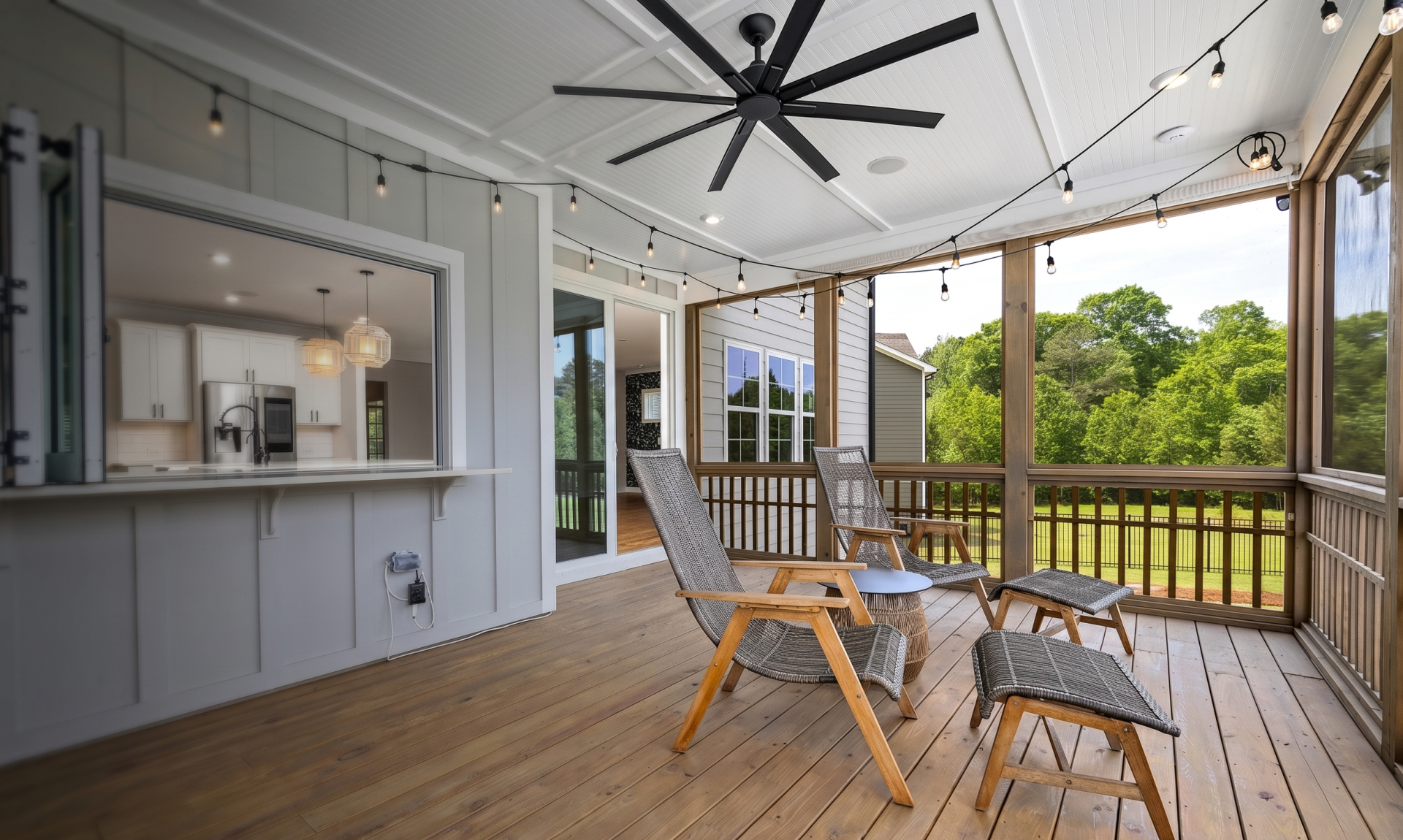 Inviting porch with modern design featuring wooden chairs, ceiling fan, and scenic view.